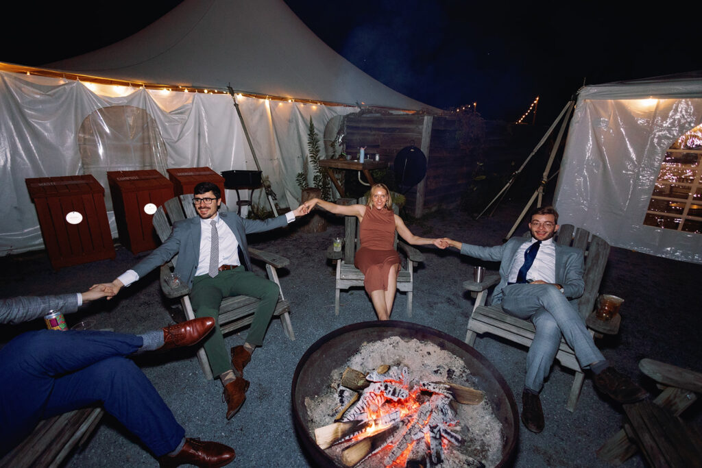 guests hanging out by a fire at a laid back glamping wedding